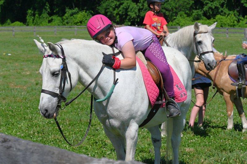 Child riding and hugging a pony at pony camp
