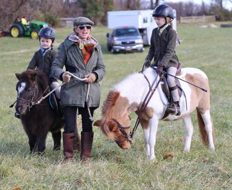 2 juniors in foxhunting attire on ponies, one is being led
