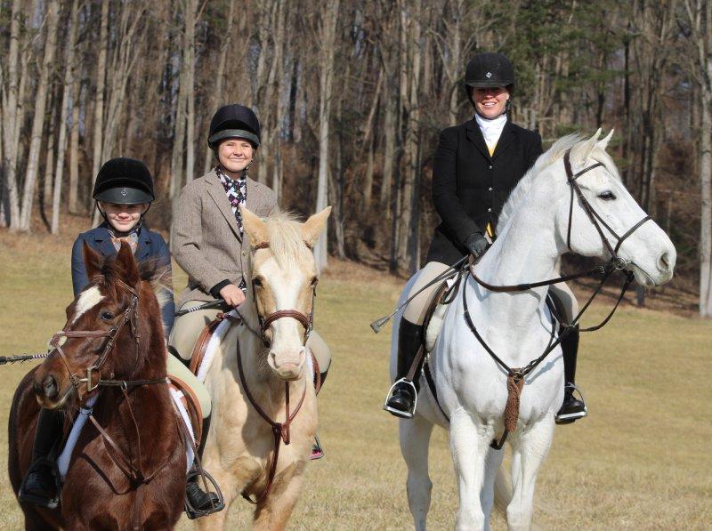 3 juniors in fox hunting attire riding horses